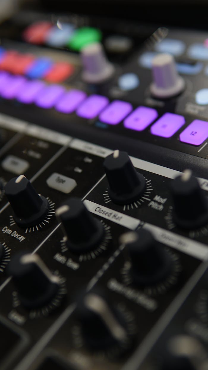 about-me-01 Detailed close-up of an audio mixer with illuminated colorful control buttons.